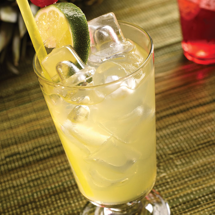 Lemon drink with ice cubes and a lime slice on a bamboo mat.